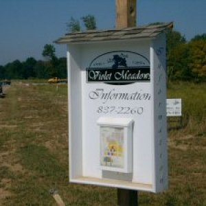 Wooden sign with shingled roof.